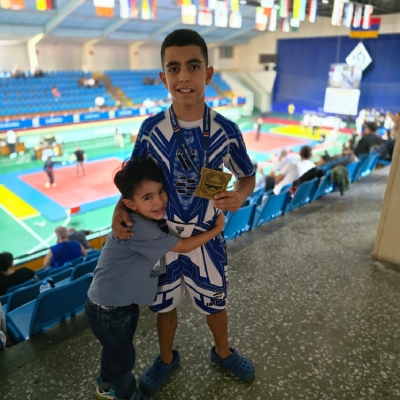 Gold medalist Mark Ghambaryan celebrating his Jiu-Jitsu Armenian Open victory with his younger brother Artem Ghambaryan, both smiling happily.