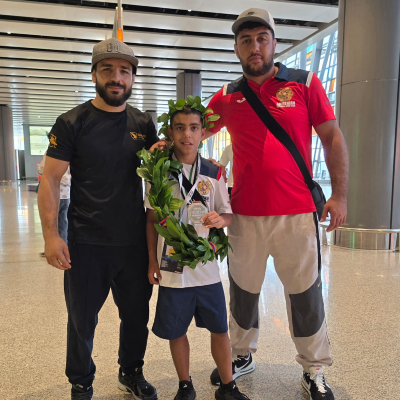 Mark Ghambaryan at the airport with coaches Arthur Zakaryan and Mayis Nersesyan after the IMMAF World Championship 2025